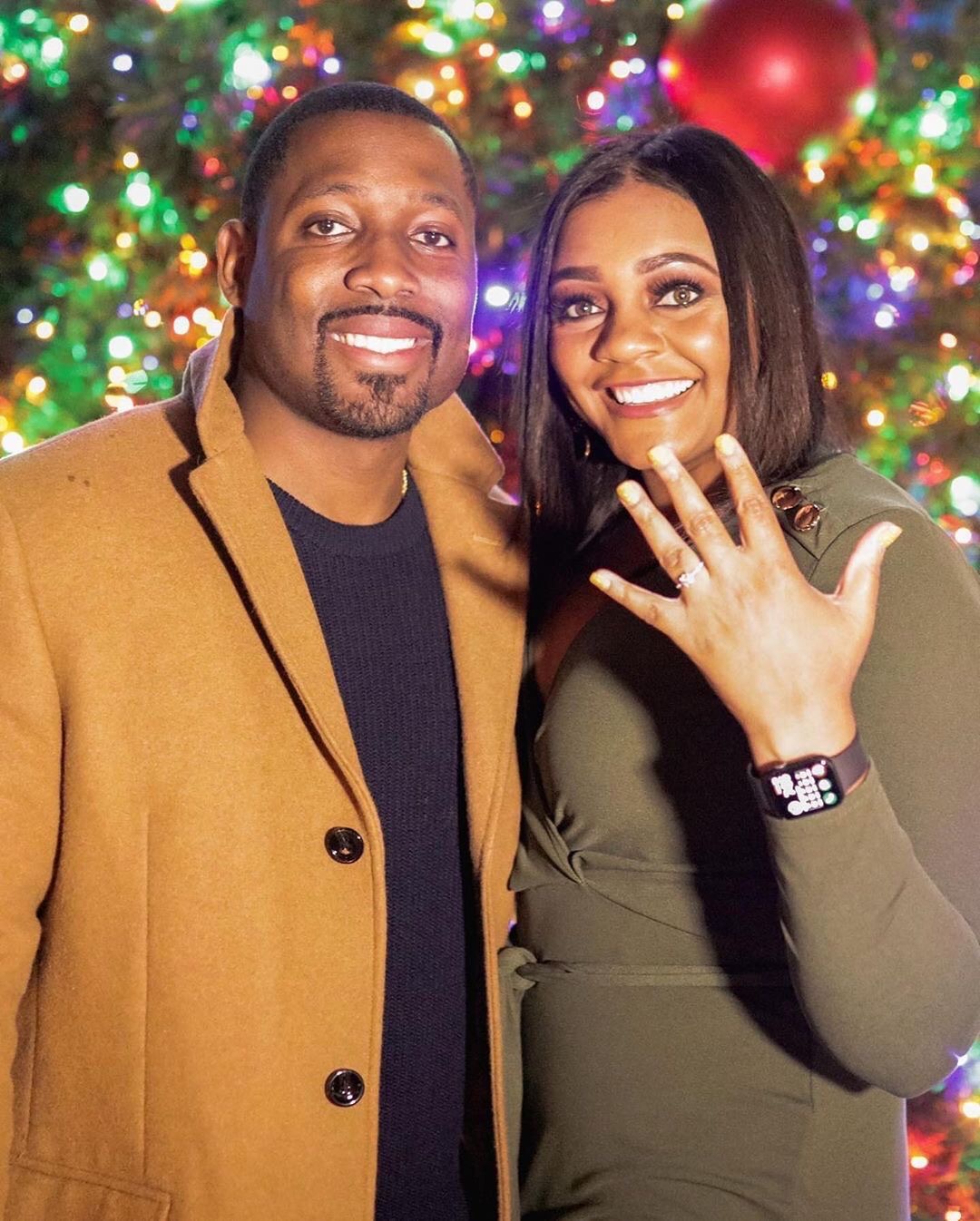 A couple celebrating their engagement by the lights